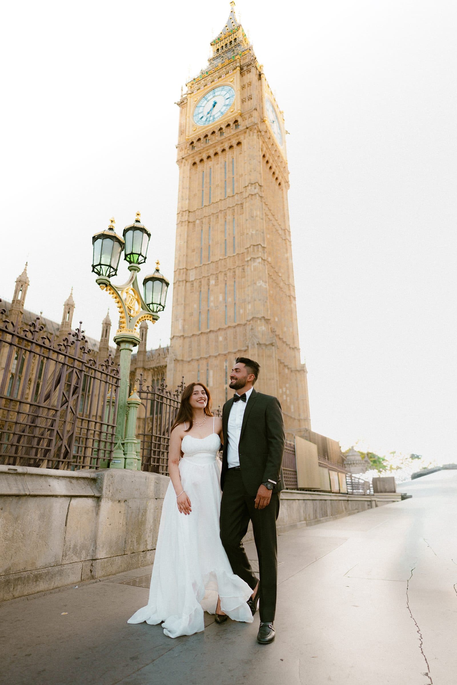 A couple beneath an ornate lamp post on Westminster Bridge, Big Ben glowing behind them