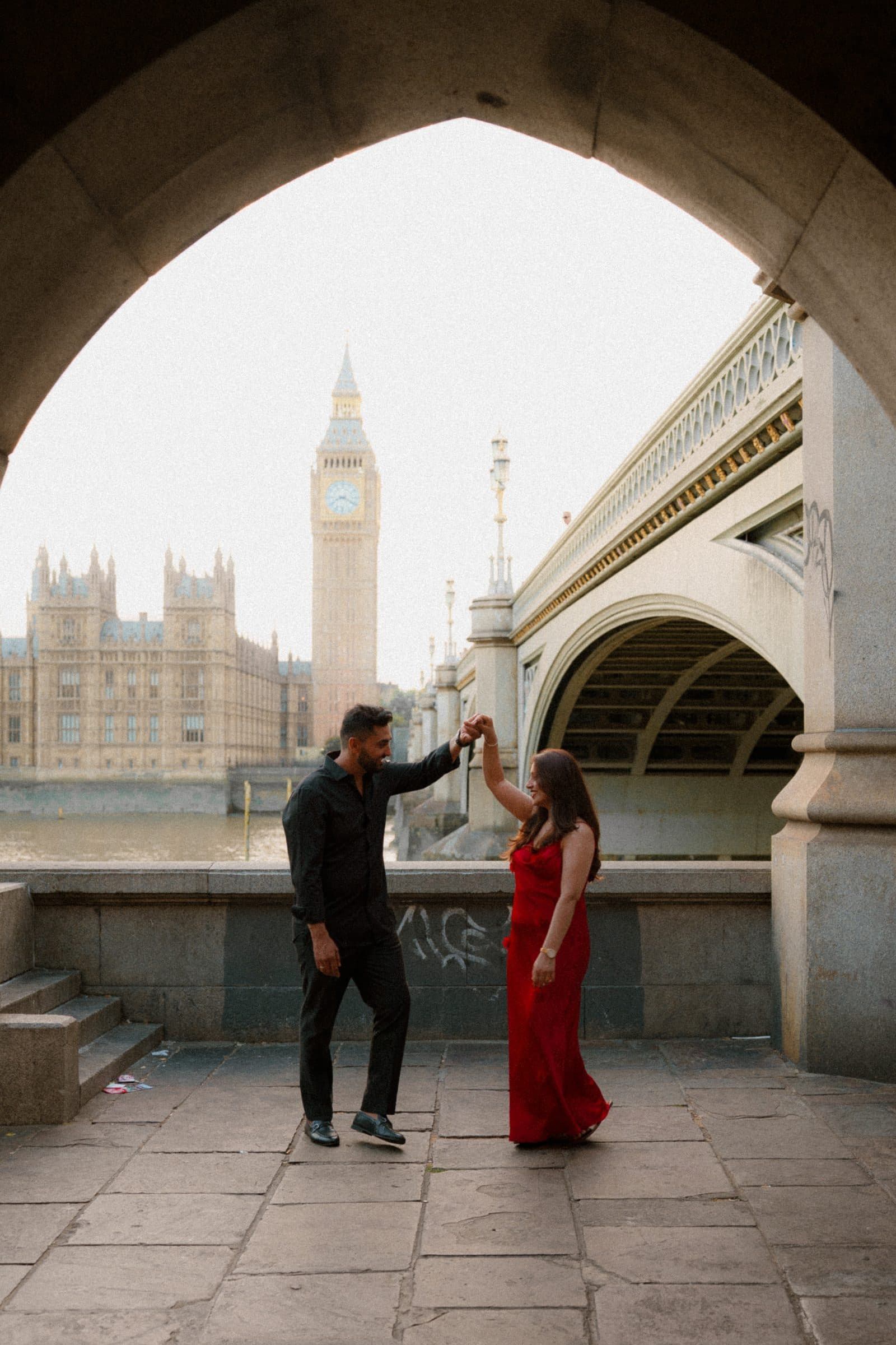 A couple dancing beneath a stone arch on the South Bank, Big Ben framed in the opening